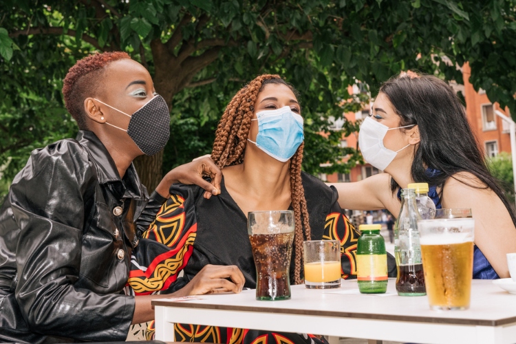 A group of three people wearing masks and drinking beer