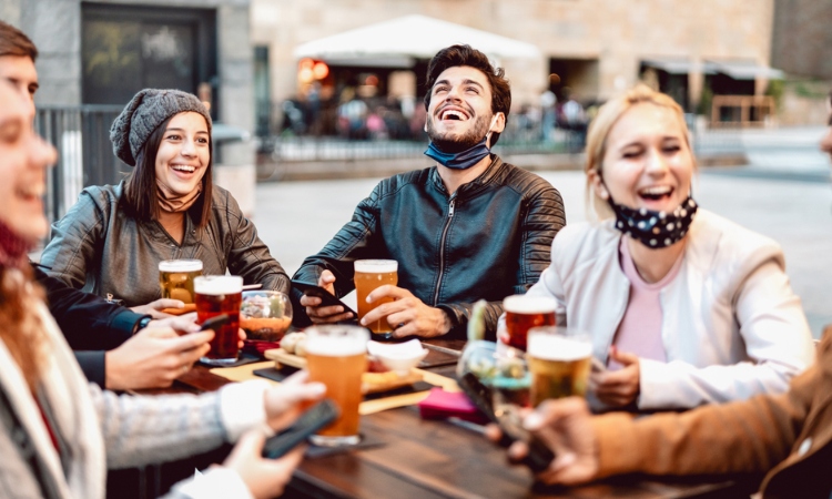 A group of four people laughing, talking and drinking beer