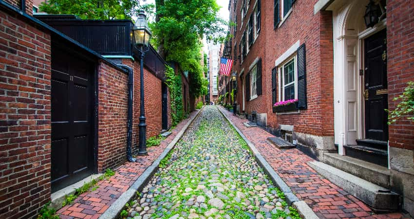 A mossy cobblestone street lined with red-brick houses in Beacon Hill, Boston