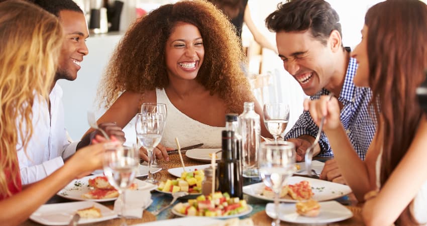 A group of friends eat and laugh in a bright restaurant