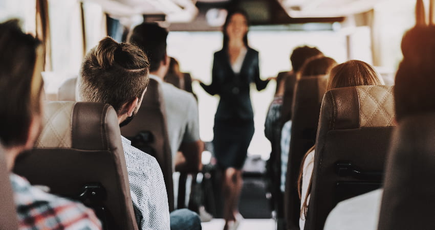 A tour guide talks to a charter bus full of passengers