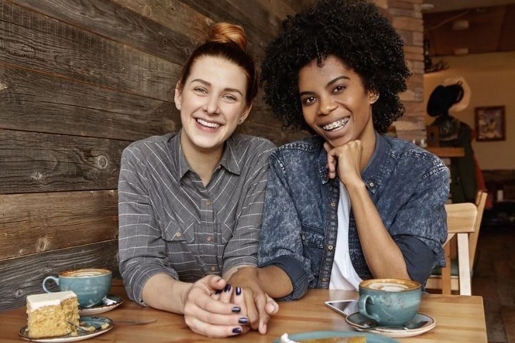 lesbian couple holding hands at a coffee shop