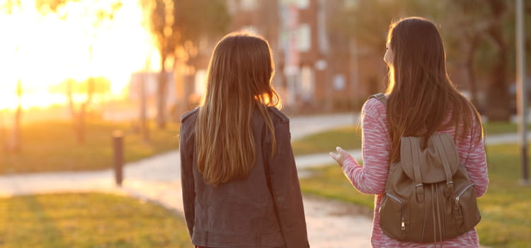 two friends stroll on a park path at dusk