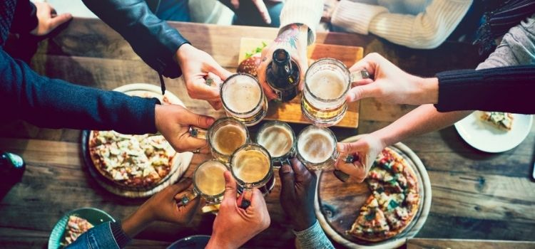 group clinking beer glasses at a group dinner at a brewery