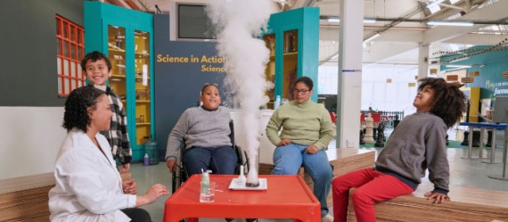 kids watch an experiment let off smoke at a science museum